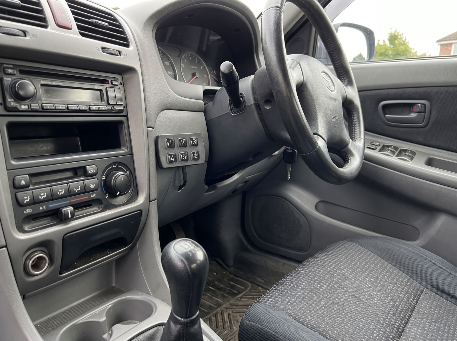 Engine keypad immobiliser keypad mounted discreetly beside the steering column in a right-hand drive vehicle for secure PIN code entry.