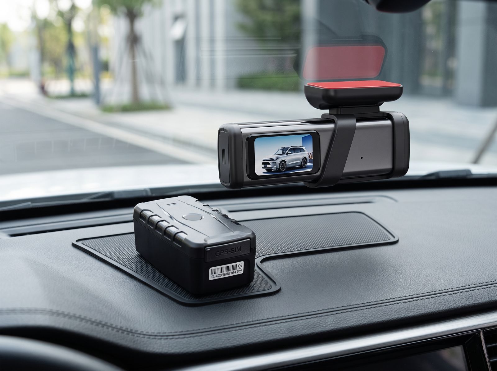 GPS tracker and dash cam installed on a car dashboard, showing a discreet vehicle tracking device beside a front-facing dashboard camera.