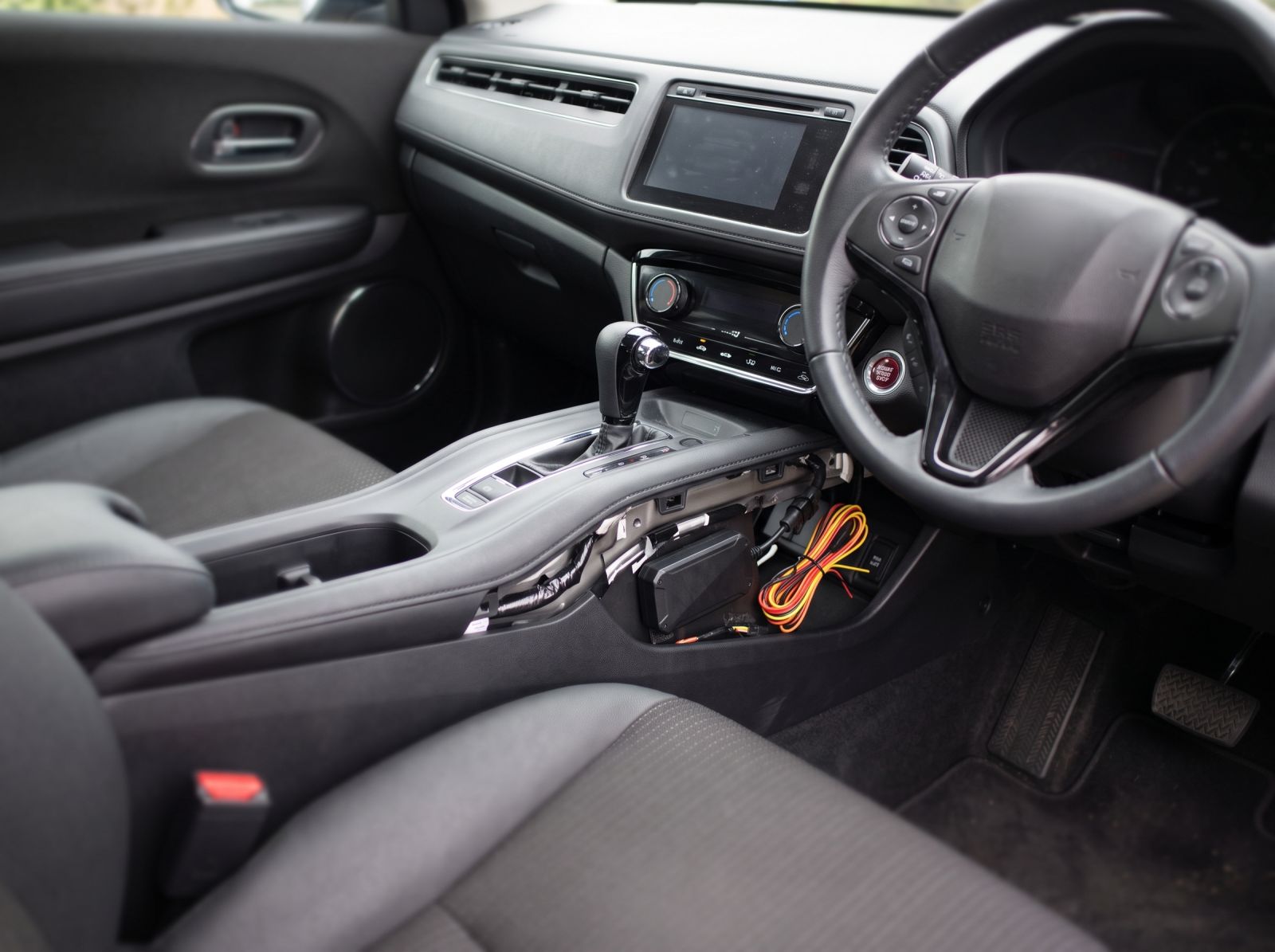 Hidden GPS tracker installed beneath a vehicle centre console with concealed wiring for discreet real-time vehicle tracking.