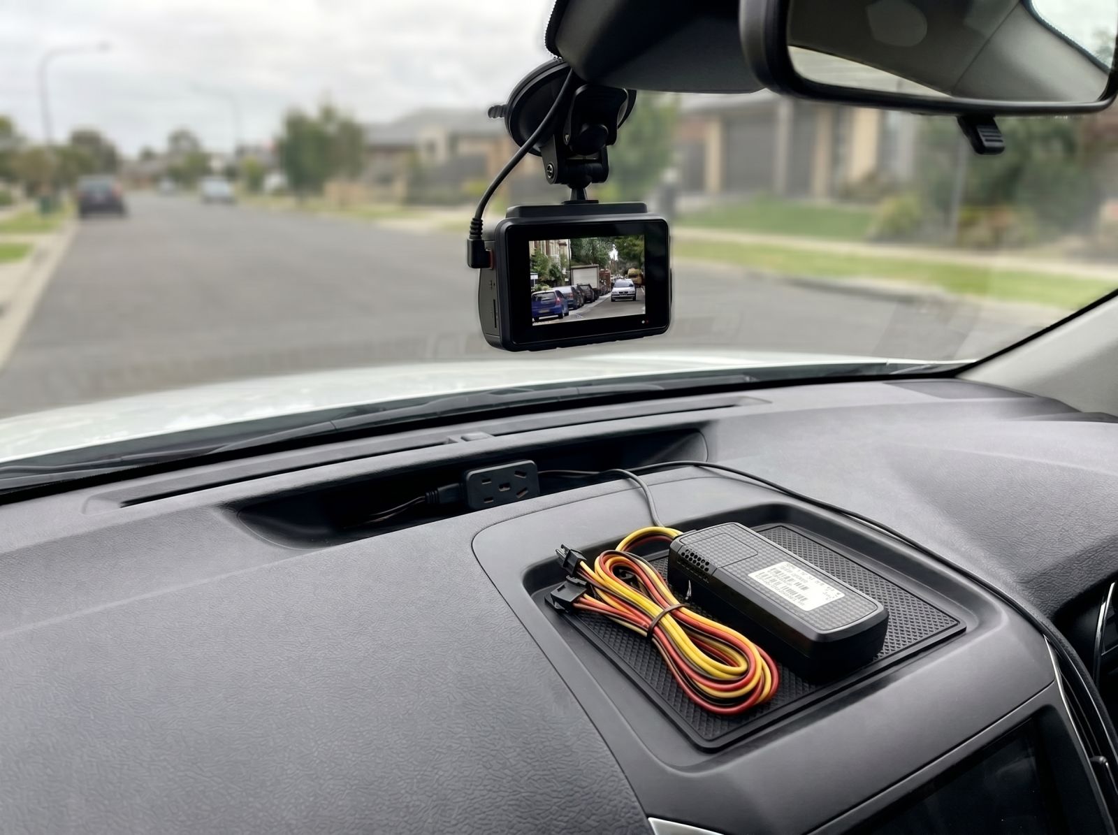 Hardwired dash cam installed on a vehicle windscreen with a concealed power module and wiring for continuous recording.