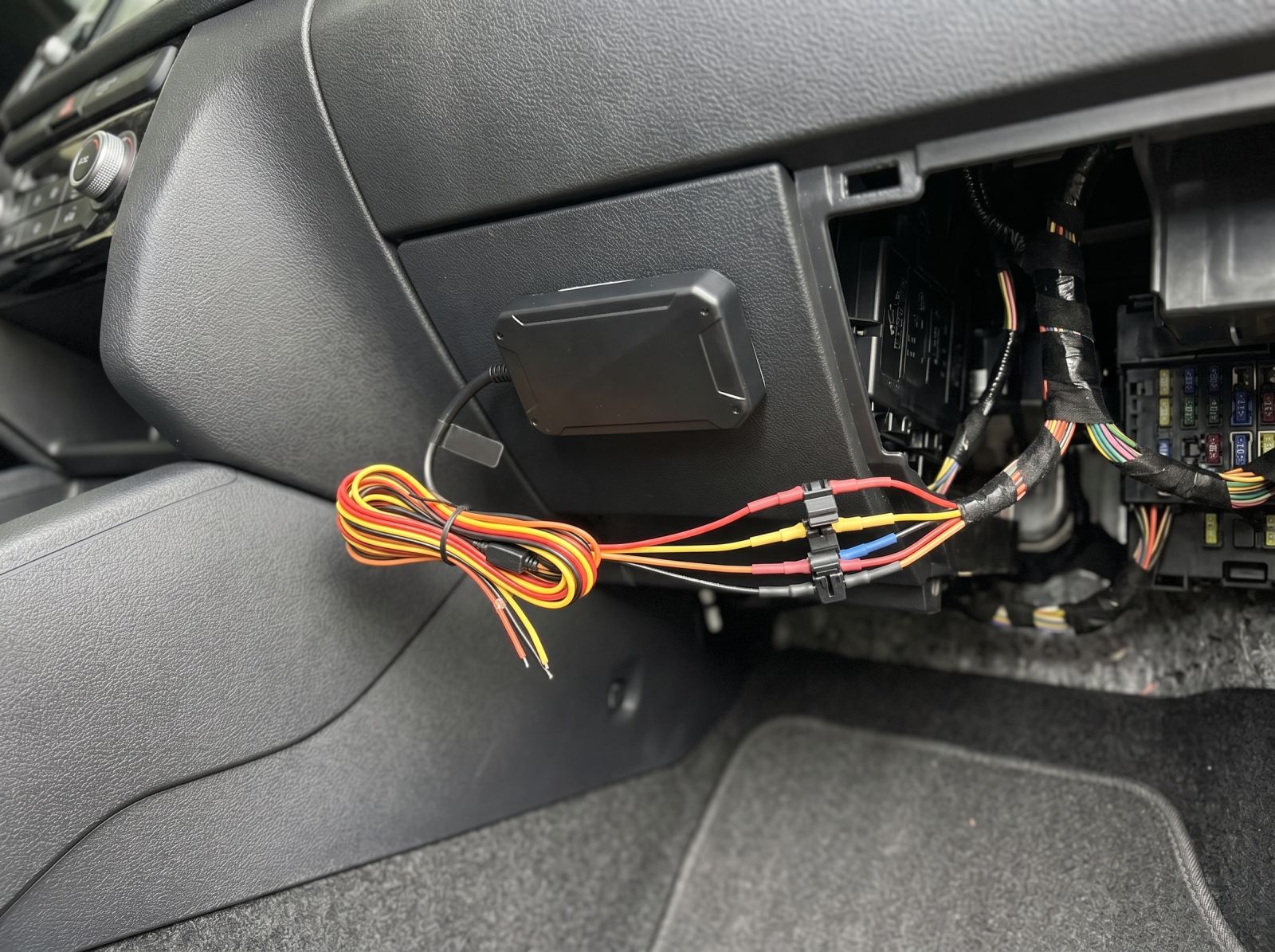 idden GPS tracker hardwired beneath a car dashboard with neatly routed wiring for discreet vehicle tracking.