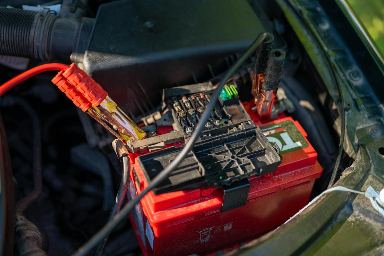 terminals of a jump starter attached to a car battery