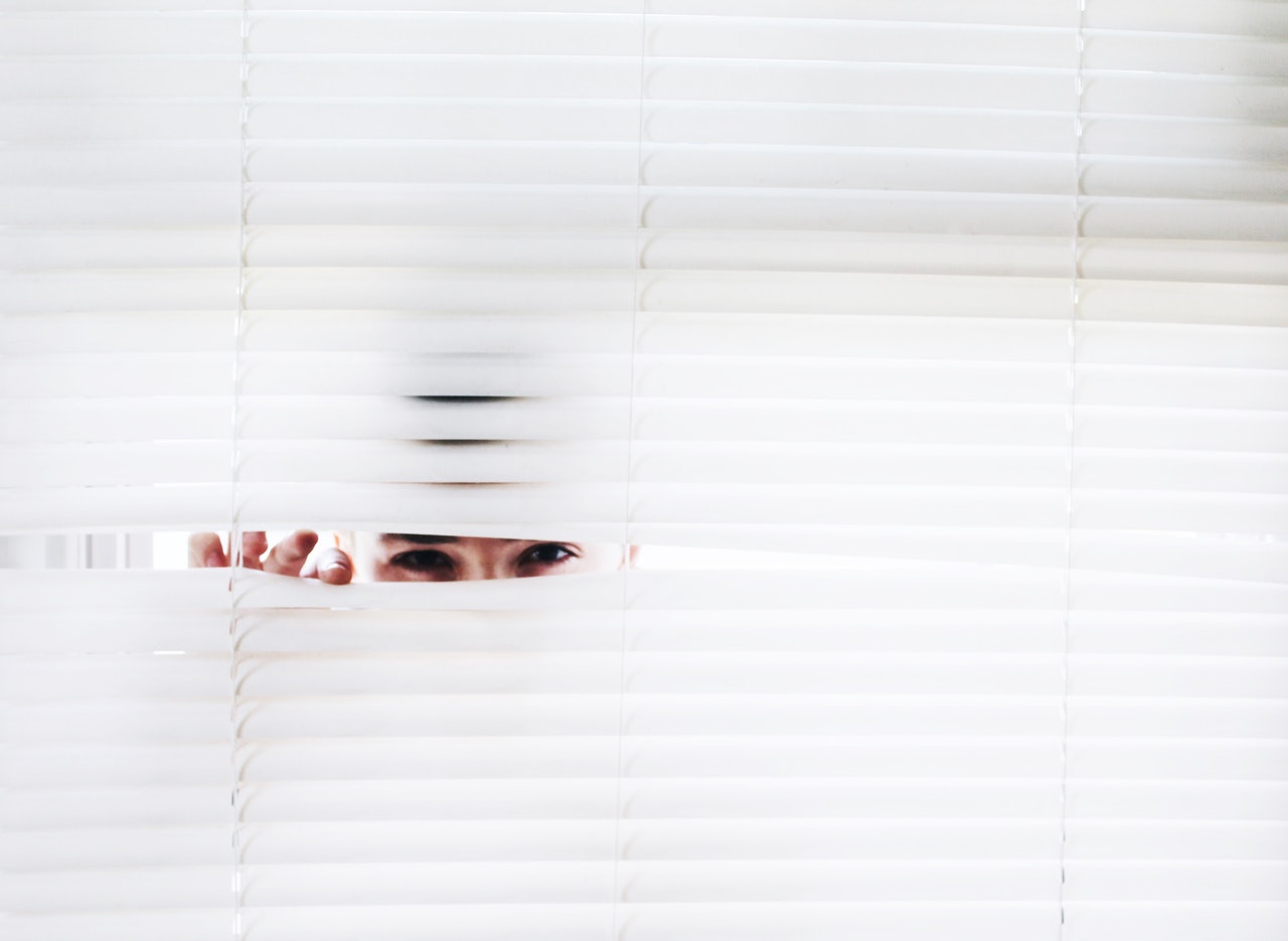 person peeking through blinds
