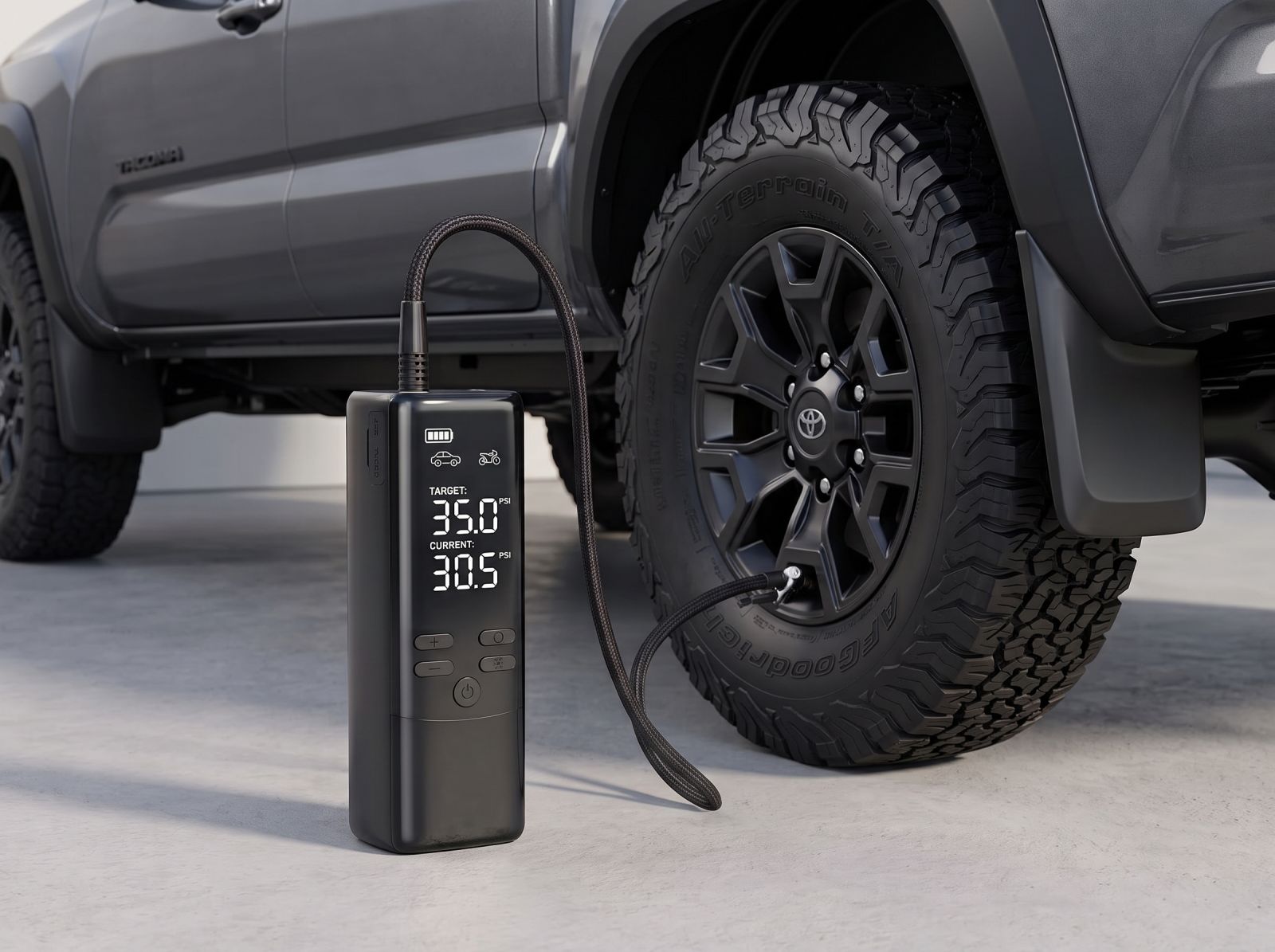 Portable cordless tyre inflator connected to an off-road truck tyre with digital pressure display