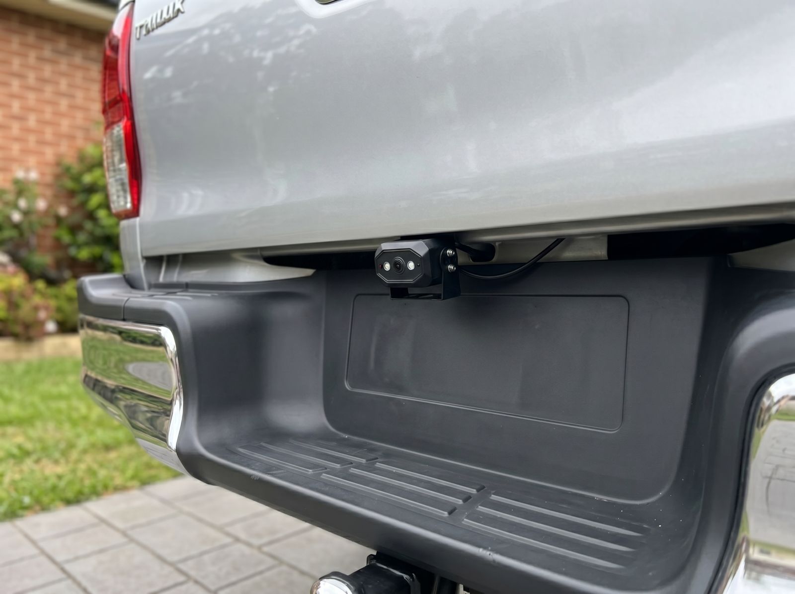 Rear-mounted reverse camera installed under the tailgate of a silver ute for improved reversing visibility