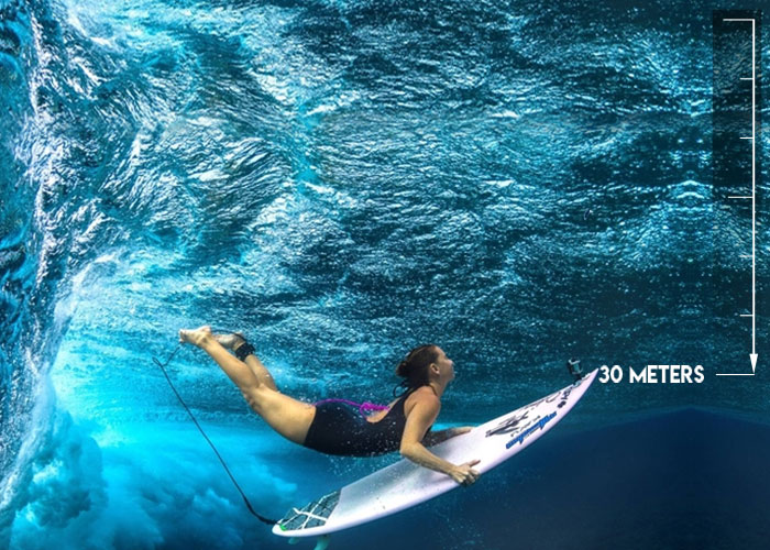 woman surfing with action camera on tip of surfboard, labelled "waterproof level 30m underwater