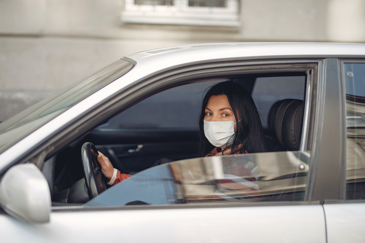woman with face mask driving car